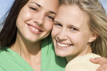 two-young-women-embracing-at-beach_Ht2W7a_RHi-1024x1024